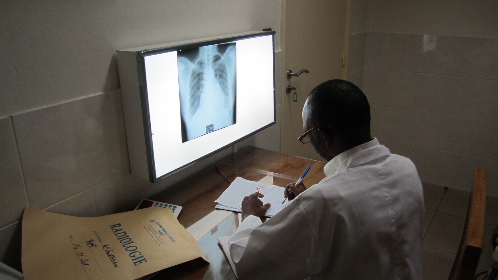 médico de Costa de Marfil revisando las pruebas de un paciente